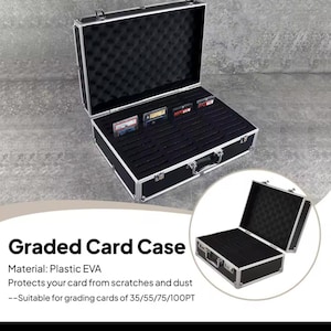 May include: A black Graded Card Case with a silver trim, open to reveal a black interior with foam padding and card slots. The case is designed to protect cards from scratches and dust. The text "Graded Card Case" is visible.