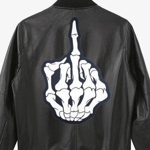 May include: Black leather jacket with a white skeleton hand giving the middle finger patch on the back.