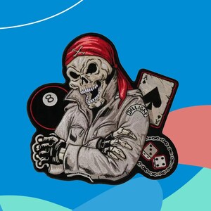 Può includere: Toppa ricamata raffigurante un teschio con una bandana rossa e una giacca grigia. La toppa include una palla otto nera, una carta da gioco, dadi e la scritta "Dilligas".