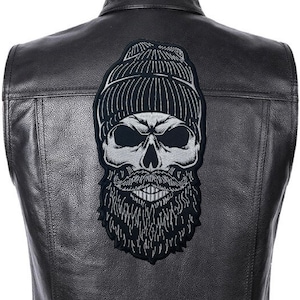 Può includere: Una toppa ricamata in bianco e nero di un teschio con un berretto e una barba. La toppa è su un giubbotto di pelle nero.