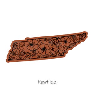 May include: A brown outline of the state of Tennessee with a floral design in black. The text "Rawhide" is below the state outline.