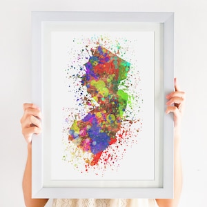 May include: A colorful watercolor painting of the state of New Jersey. The painting is in a white frame and is being held by a person.