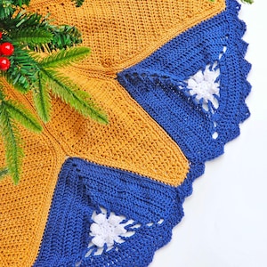 May include: A crocheted Christmas tree skirt in blue and gold with a white crocheted flower design.
