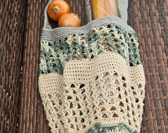 May include: A crocheted market bag with a green and beige pattern. The bag is filled with a loaf of bread and two onions.