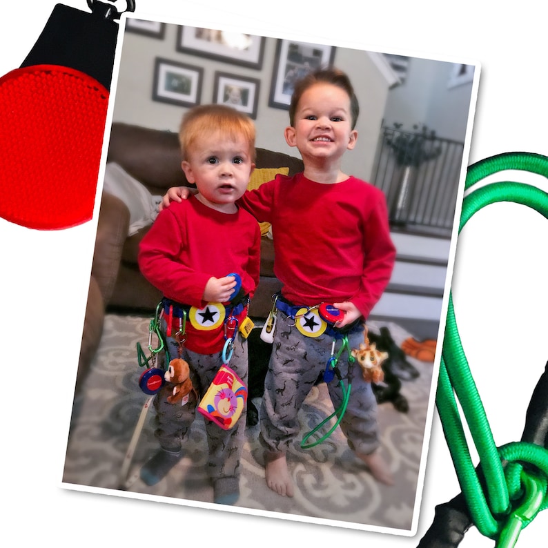 May include: Two young boys wearing red shirts and blue and yellow patterned belts with various toys attached. The boys are standing in a living room with a brown couch and a green rug.