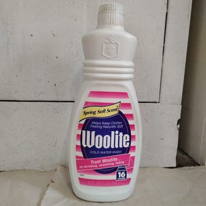 May include: A white plastic bottle of Woolite cold water wash laundry detergent. The bottle has a pink and white label with the text "Spring Soft Scent" and "Woolite". It contains 22 fl oz (650 ml) and is designed for 16 loads.