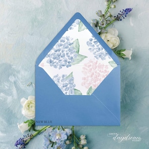 May include: A blue envelope with a floral hydrangea pattern inside. The envelope is surrounded by white and blue flowers on a light blue background. The text "NEW BLUE" is visible on the bottom left.