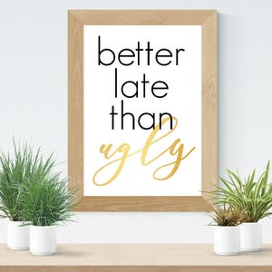 May include: A framed print with the text "better late than ugly" in black and gold lettering on a white background.