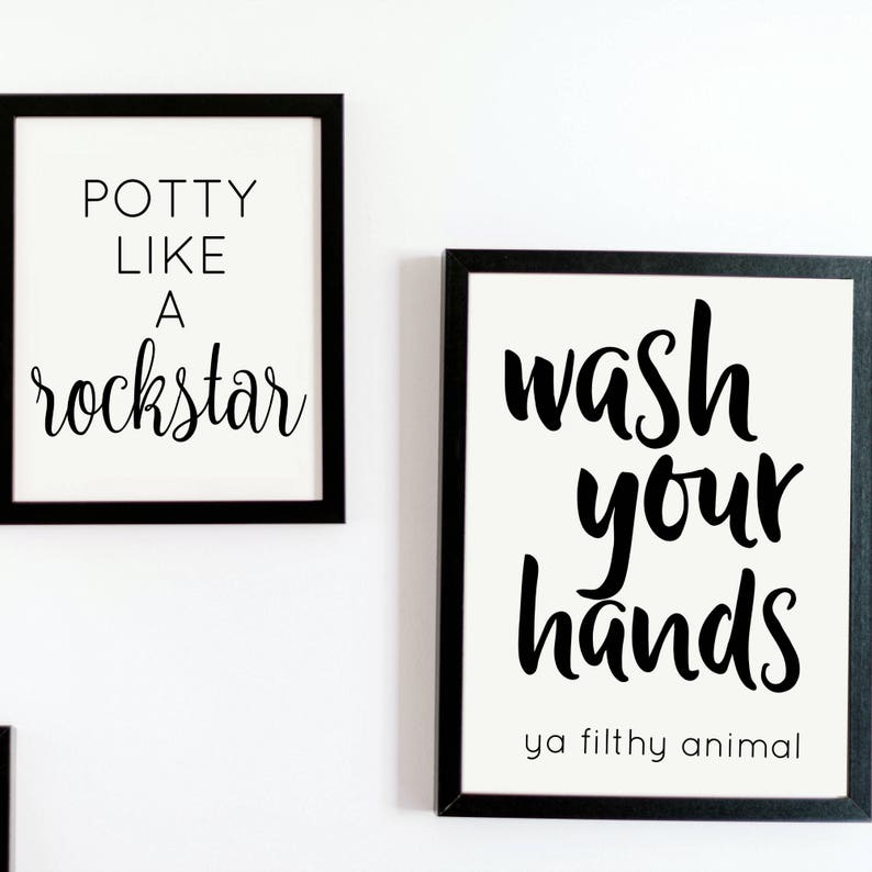 May include: Two framed wall art prints with black frames. One print reads "Potty Like A Rockstar" in black script. The other print says "Wash Your Hands ya filthy animal" in black script.