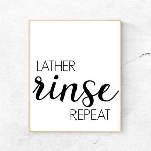 May include: Black and white typography print with the text "LATHER rinse REPEAT" on a white background with a thin gold frame.