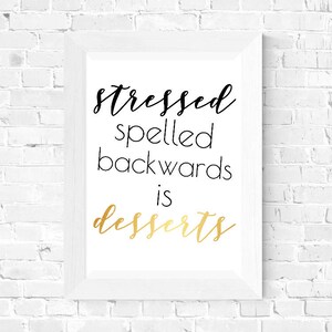 May include: White framed print with black text that reads "stressed spelled backwards is desserts" with the word "desserts" in gold lettering.