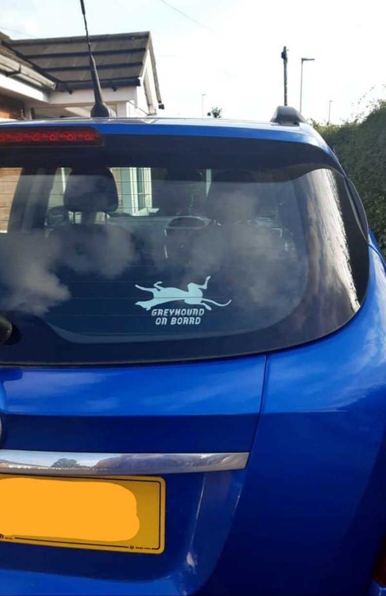 Peut inclure: Une voiture bleue avec un autocollant blanc sur la vitre arri&egrave;re qui dit "Greyhound on Board". L'autocollant repr&eacute;sente une silhouette de l&eacute;vrier courant.