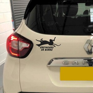 Peut inclure: Une voiture blanche avec une silhouette noire de l&eacute;vrier et le texte "Greyhound on Board" sur la vitre arri&egrave;re.