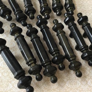 May include: A set of black cabinet handles with an ornate design. The handles have a dark finish with a metallic shimmer. Mounting screws are included. These handles are suitable for various furniture projects, ready to install.