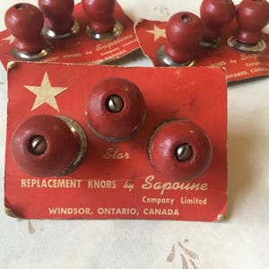 May include: Three red wooden knobs with silver metal bases on a red and white card. The card reads "Replacement Knobs by Sapoune Company Limited Windsor, Ontario, Canada".