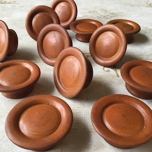 Op de afbeelding: Een verzameling houten kastknoppen in een warme bruine tint. De knoppen hebben een afgerond, hoedachtig ontwerp met een platte bovenkant en een korte, cilindrische basis. Geschikt voor meubels of decoratieve doeleinden.