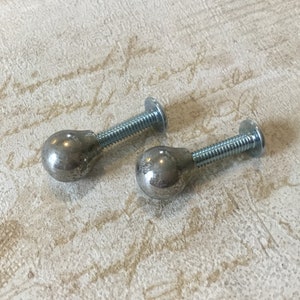 May include: Two silver metal knobs with a round ball shape and a screw thread. The knobs are on a white background.