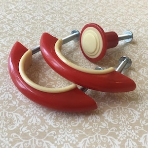 Piccola coppia di maniglie per armadietti vintage in plastica, rosse e bianche, stile Art Déco, da 2 7/8”, con lati scanalati e gradini, risalenti agli anni '40/'50, con pomello di montaggio singolo.