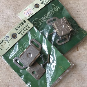 May include: Two packs of Amerock magnetic catches, each containing a silver magnetic catch, two screws, and a metal plate. The packs are green and have the product number E9783 printed on them.