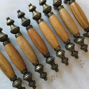 May include: Nine wooden drawer pulls with brass accents. The pulls have a light brown wood finish and are approximately 7.5 cm long.