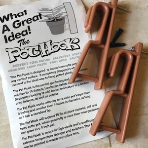 May include: A brown plastic pot hook designed to hang terracotta pots. The hook is designed to disappear when in use and is ideal for patios, backyards, decks, windows, lamp posts, pool areas, and balconies. The text on the packaging reads "What A Great Idea! The Pot Hook".
