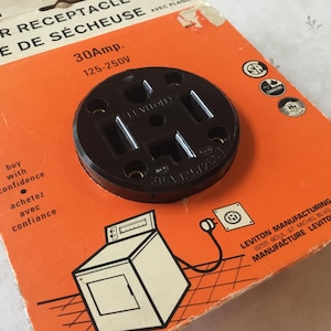 May include: A black 30 amp dryer outlet with a white label that reads "LEVITON DRYER RECEPTACLE PRISE DE SÉCHEUSE 30Amp. 125-250V". The outlet is on a bright orange background with the text "buy with confidence achetez avec confiance" and a small illustration of a dryer.