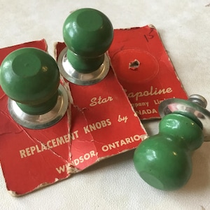 May include: Three green replacement knobs for furniture with silver bases. The knobs are packaged on a red card with the text "Star Replacement Knobs by Tapoline Company Limited, Windsor, Ontario, Canada".