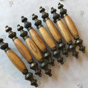 May include: Nine antique wooden cabinet knobs with brass accents. The knobs have a light brown wood finish and a slightly distressed look.