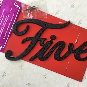 May include: A black plastic house number "Five" on a red background. The number is raised and has a textured surface. The packaging includes instructions and a 15-year free replacement guarantee.