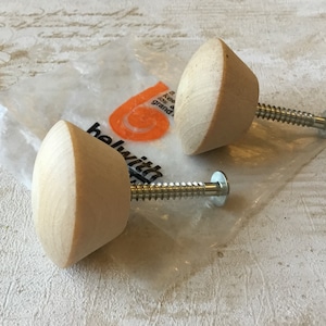 May include: Two wooden knobs with screws, packaged in a clear plastic bag. The knobs are light brown and have a rounded, slightly conical shape. The bag has a label with the text "helwit" and a logo.