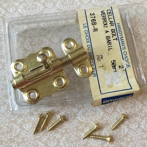 May include: A brass-colored cellar bolt with matching screws, packaged in a clear plastic container. The label reads "CELLAR BOLT" and "HANDYMAN'S CHOICE".
