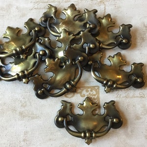 May include: A collection of antique brass drawer pulls. Each pull features a decorative leaf design with a curved handle. The pulls are in various positions, showcasing their intricate details and aged finish. Ideal for vintage furniture restoration.
