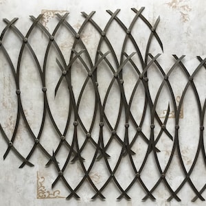 Puede incluir: Un conjunto de paneles decorativos de pared de metal negro con un diseño de celosía curvado. Los paneles están hechos de finas varillas de metal entrelazadas para crear un patrón geométrico.