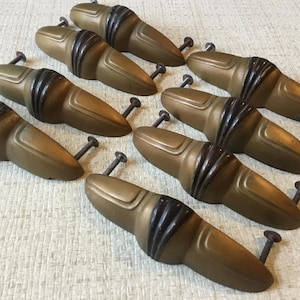 May include: Eight antique brass cabinet pulls with black accents. The pulls are shaped like a teardrop with a rounded top and a pointed bottom. They have a vintage look and would be perfect for adding a touch of elegance to any home.