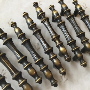 May include: A set of ten antique brass cabinet knobs with a decorative, fluted design. The knobs have a dark patina and a slightly aged look.