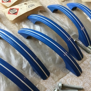 Peut inclure: Ensemble de poignées de meubles bleues avec une bande blanche centrale. Les poignées incurvées sont accompagnées de vis argentées. Quincaillerie vintage.
