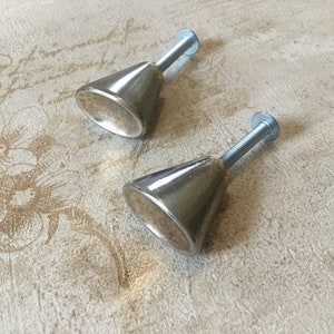 Peut inclure: Deux boutons de cabinet en forme de cône argentés avec des vis.