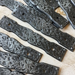 May include: A set of 10 black metal straps with a hammered finish. Each strap has two holes and a slightly curved shape.