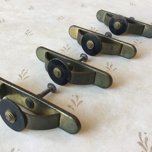 May include: Four antique brass cabinet door pulls with black round knobs. The pulls are in the shape of a half-circle.