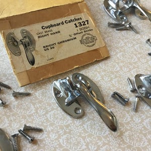 May include: A selection of bright chromium cupboard catches with screws, and a vintage box. The box reads "Cupboard Catches 1327" and "Bright Chromium US 26". The hardware is for right-hand use.
