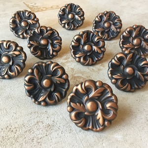May include: Twelve ornate copper cabinet knobs with a black finish and a floral design.