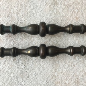 May include: Two antique brass cabinet pulls with a decorative, fluted design. The pulls are approximately 4 inches long and have a slightly aged patina.