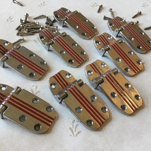 May include: Set of ten antique silver-toned door hinges with red stripes. The hinges are in good condition and have a vintage look.