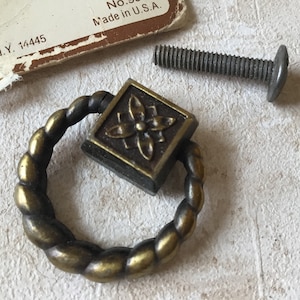 Puede incluir: Un pomo de armario de metal dorado con un diseño de cuerda y una placa cuadrada con un diseño floral. El pomo viene con un tornillo.