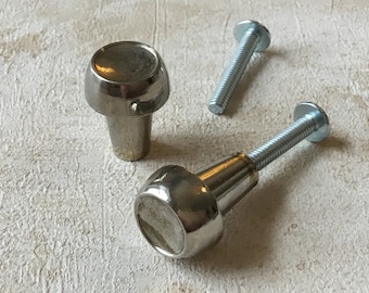 Puede incluir: Dos pomos de armario plateados con tornillos. Los pomos son redondos con un centro elevado y un acabado liso.