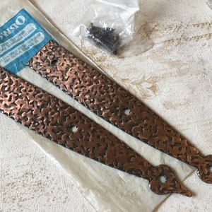 以下が含まれることがあります： 丸みを帯びた端と2つの穴がそれぞれある、ハンマーで叩かれた銅製のヒンジストラップ2本。ストラップは、ネジ付きの透明なビニール袋に入っています。