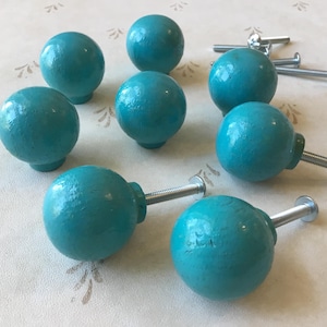 Peut inclure: Dix boutons de porte ronds en bois bleu turquoise avec des vis en métal argenté.