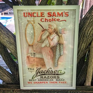 Könnte beinhalten: Gerahmte Vintage-Werbung für "Uncle Sam's Choice" Rasierer. Die Illustration zeigt Uncle Sam beim Rasieren. Der Text lautet "Best American Make. We Sharpen Them Free."