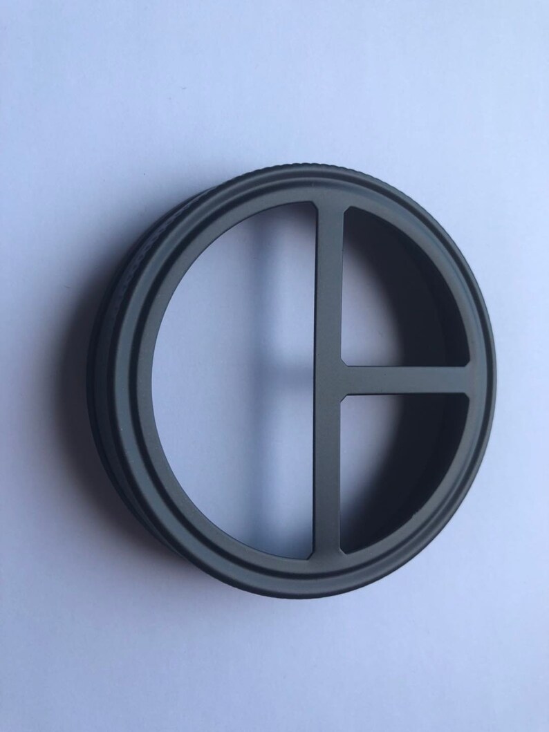 Puede incluir: Anillo de metal negro con un dise&ntilde;o circular que presenta tres recortes. El anillo tiene un acabado liso y pulido.