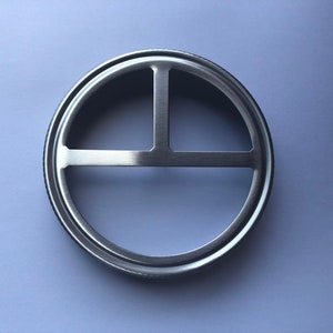 Puede incluir: Un anillo de metal plateado con un dise&ntilde;o circular que presenta tres barras que se cruzan. El anillo est&aacute; dise&ntilde;ado para encajar sobre una tapa de frasco.